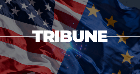 Le mot 'Tribune' en blanc centré sur une image divisée entre le drapeau des États-Unis à gauche et le drapeau de l’Union européenne à droite, avec un effet lumineux au centre.